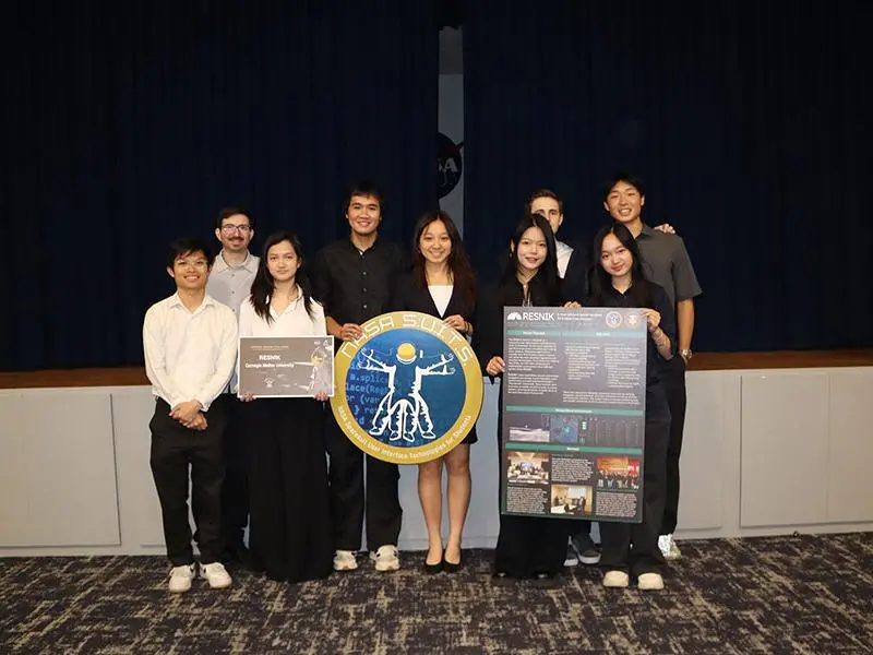 Group shot of the students on Team Resnik, holding their poster and the NASA SUITS seal.